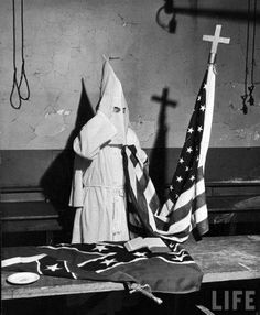 a black and white photo of an american flag on a table next to a crucifix