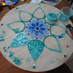 a wooden table topped with lots of blue and green mosaics on top of it