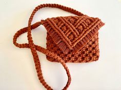 a crocheted brown purse sitting on top of a white table next to a string