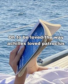 a person reading a book on top of a boat in the ocean with text that reads oh to be loved the way achilles loved patroclus