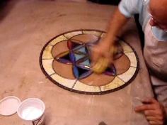 a man with an apron on working on a mosaic tile design in a kitchen area