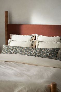 a bed with white sheets and brown headboard