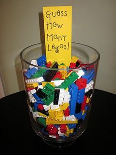 a glass filled with lots of legos on top of a black table next to a yellow sign