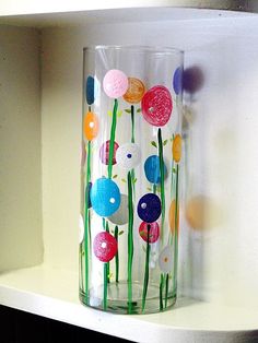 a glass with flowers painted on it is sitting on a shelf next to a window