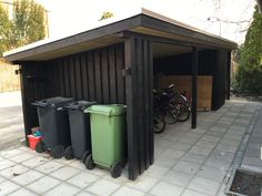 three trash cans and two bicycles are parked in a shed on the side of the road