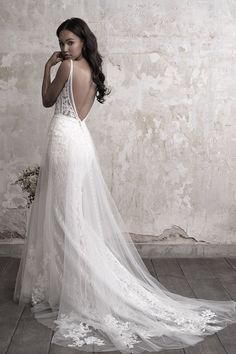 a woman in a white wedding dress standing on the floor with her back to the camera