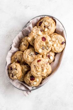 white chocolate cranberry cookies in a metal bowl on a marble countertop with a cloth