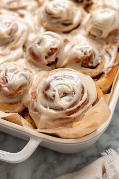 a pan filled with cinnamon rolls covered in icing