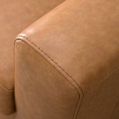 the back end of a brown leather couch with stitching on it's arm