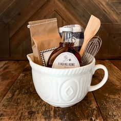 a white bowl filled with cooking utensils on top of a wooden table next to a brown bag