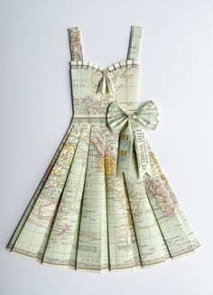 a dress made out of maps with a bow on the front and back, sitting on top of a white surface