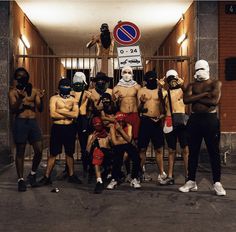 a group of men standing next to each other in front of a gate with masks on