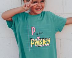 Stay on-trend this school year with this custom back-to-school shirt. The fun color scheme, retro design and addition of your grade level and name make this t-shirt extra special. Let's get this amazing shirt for your kids to start a new wonderful school year! We are working with 2 different brands for each type of shirt. Below are different specific descriptions for each of them, please kindly read to get details: +Youth T-shirt: - 3.7 oz., 100% airlume combed and ringspun cotton - Double-needle stitching throughout - Taped shoulder-to-shoulder - Seamless rib at neck +Toddler's T-shirt: - 4.5 oz./yd², 100% combed ringspun cotton fine jersey - Topstitched ribbed collar - Shoulder-to-shoulder self-fabric back neck tape - Double-needle sleeves and bottom hem - CPSIA-compliant tracking label Fun Green T-shirt For School, Fun School Tops With Name Print, Back To School Spirit Shirt For College, School Spirit Tops With Name Print For School Events, Back To School Name Print Tops For College, School Spirit Tops For Daycare And Back To School, Cute School Shirt With Name Print, Blue School Spirit T-shirt, Green Pre-shrunk Shirt For School