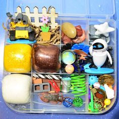 a plastic container filled with lots of toys and other items on top of a blue table