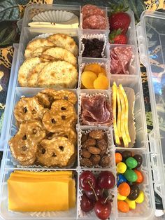 a plastic container filled with lots of different types of snacks and fruit on top of a table