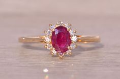 an oval shaped ruby and diamond ring on a wooden surface