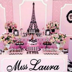 a table topped with a cake covered in pink and white frosting next to a tall eiffel tower