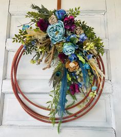 a wreath with flowers and feathers hanging on a door