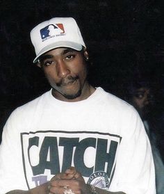 a man wearing a baseball cap and white shirt with the word catch written on it