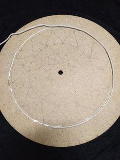 the bottom of a white disc on a black surface with wires running through it and an empty hole in the middle