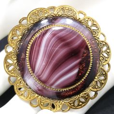 *Description: This is a beautiful Western Germany purple slag glass brooch with a filigree frame from the 1950s or late 1940s. The brooch is stamped on the clasp WESTERN GERMANY. One of the unique features of this brooch is there is a glass center framed in metal, then set in another round glass and then set in a filigree frame. This would be a great addition to your vintage jewelry collection or make a great vintage gift! *Approximate Measurements: Length & Width - 1 7/8 Inches, Weight - .6 Mid-century Cabochon Brooch For Gift, Mid-century Cabochon Brooch Gift, Mid-century Cabochon Brooches For Gifts, Vintage Filigree Brooches For Formal Occasions, Vintage Cabochon Brooch For Wedding, Vintage Cabochon Brooches For Wedding, Collectible Vintage Round Brooches, Vintage Wedding Brooches With Cabochon, Vintage Filigree Brooches