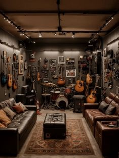 a living room filled with lots of guitars on the wall and couches in front of it