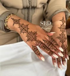 a woman's hands with henna tattoos on her hand and nails in the middle