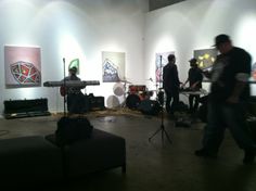 a group of people playing instruments in a room with paintings on the wall behind them