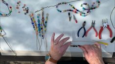 a woman is making beaded bracelets with scissors and beads on the wall behind her