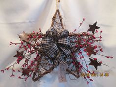 a star shaped wreath with red berries and stars hanging from it's centerpiece