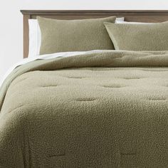 a bed with green bedspread and pillows