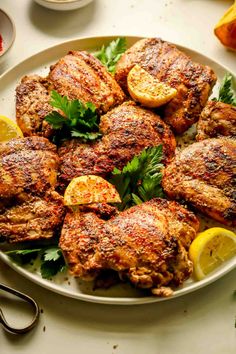 a plate full of chicken with lemons and parsley on the side for garnish