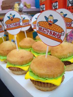 some hamburgers are sitting on a table with cupcake toppers and stickers