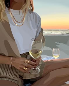 a woman sitting on the beach holding a glass of wine