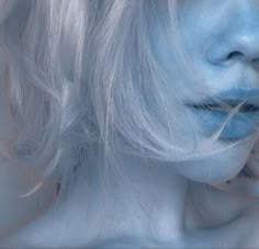 a woman with white hair and blue makeup