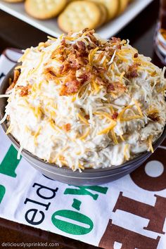 a bowl filled with food sitting on top of a table next to some crackers