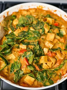 a pan filled with tofu and spinach on top of a stove