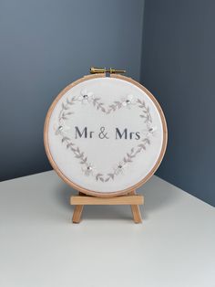 a cross - stitch heart with the word mr and mrs on it sitting on a wooden stand