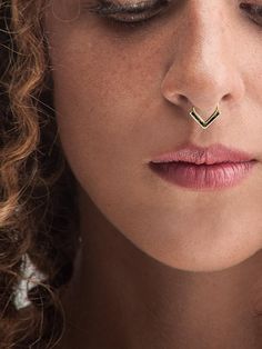 a close up of a woman with a nose ring on her nose and piercing in the middle