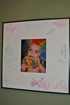 a child holding a lollipop in front of a white board with writing on it