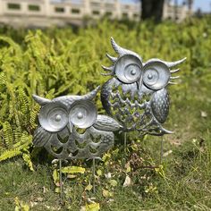 two metal owls are sitting in the grass