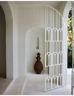 a vase sitting on top of a white shelf next to a wall with arched doorways