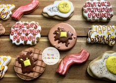 some decorated cookies are sitting on a wooden table with happy birthday written on them in different colors