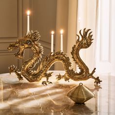 a golden dragon figurine sitting on top of a table next to some candles