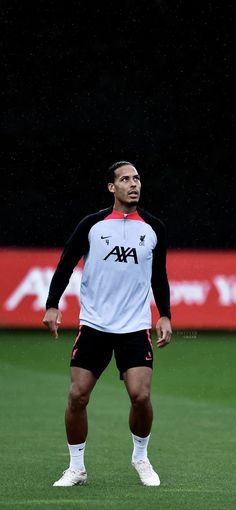 a man standing on top of a soccer field wearing black and white uniforms with red accents