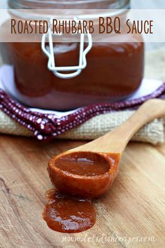 a wooden spoon filled with bbq sauce on top of a cutting board next to a jar