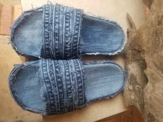 two pairs of denim slippers sitting on top of a table