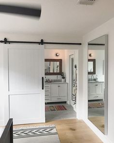 an open door leading to a bathroom with mirrors on the wall and a rug on the floor