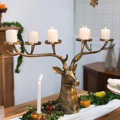 a deer head candle holder on a table with fruit and candles in front of it