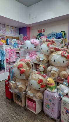 there are many stuffed animals on display in the store, and one is wearing a hello kitty hat